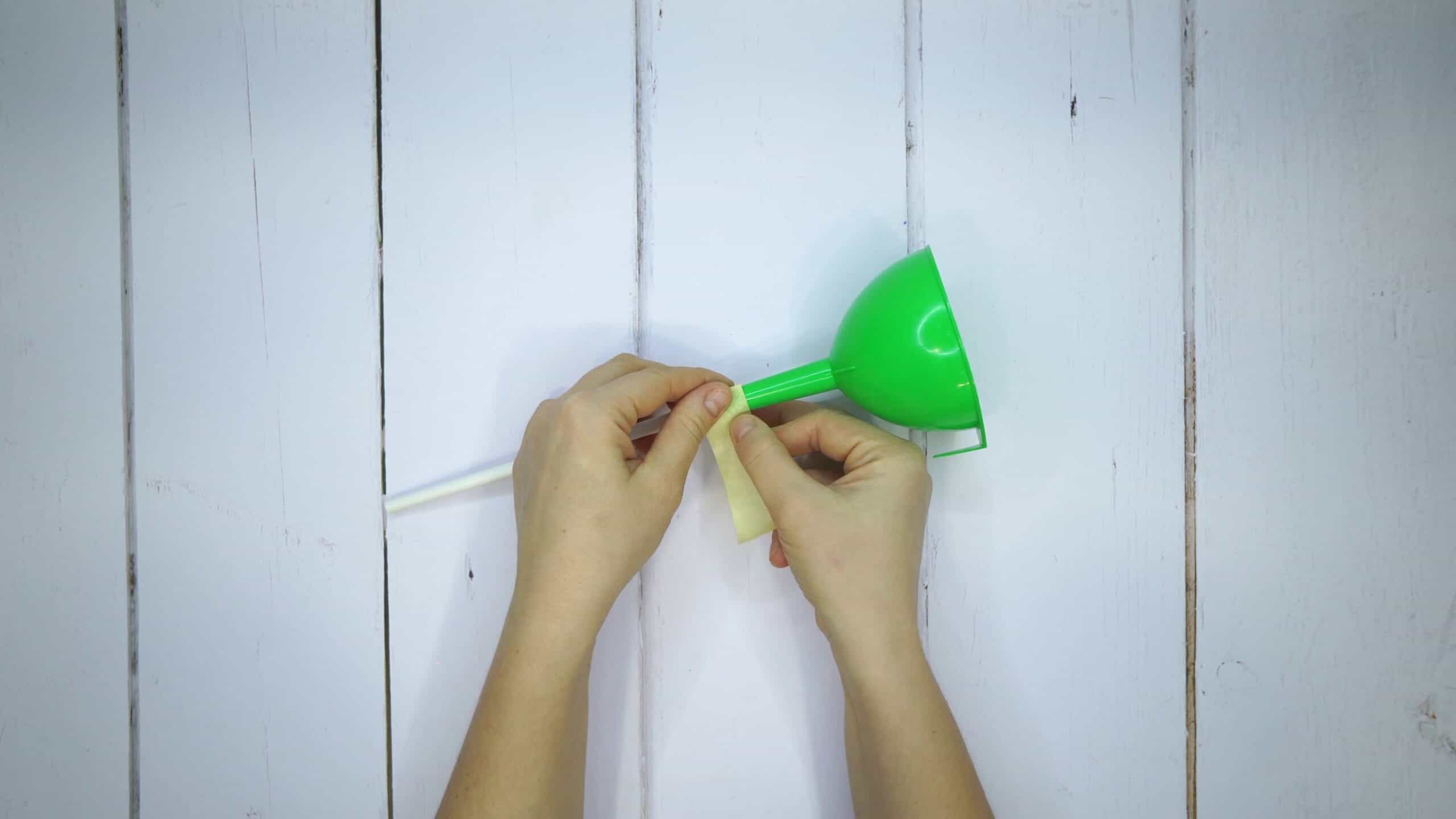 Attach the straw to the end of the funnel with some sticky tape scaled